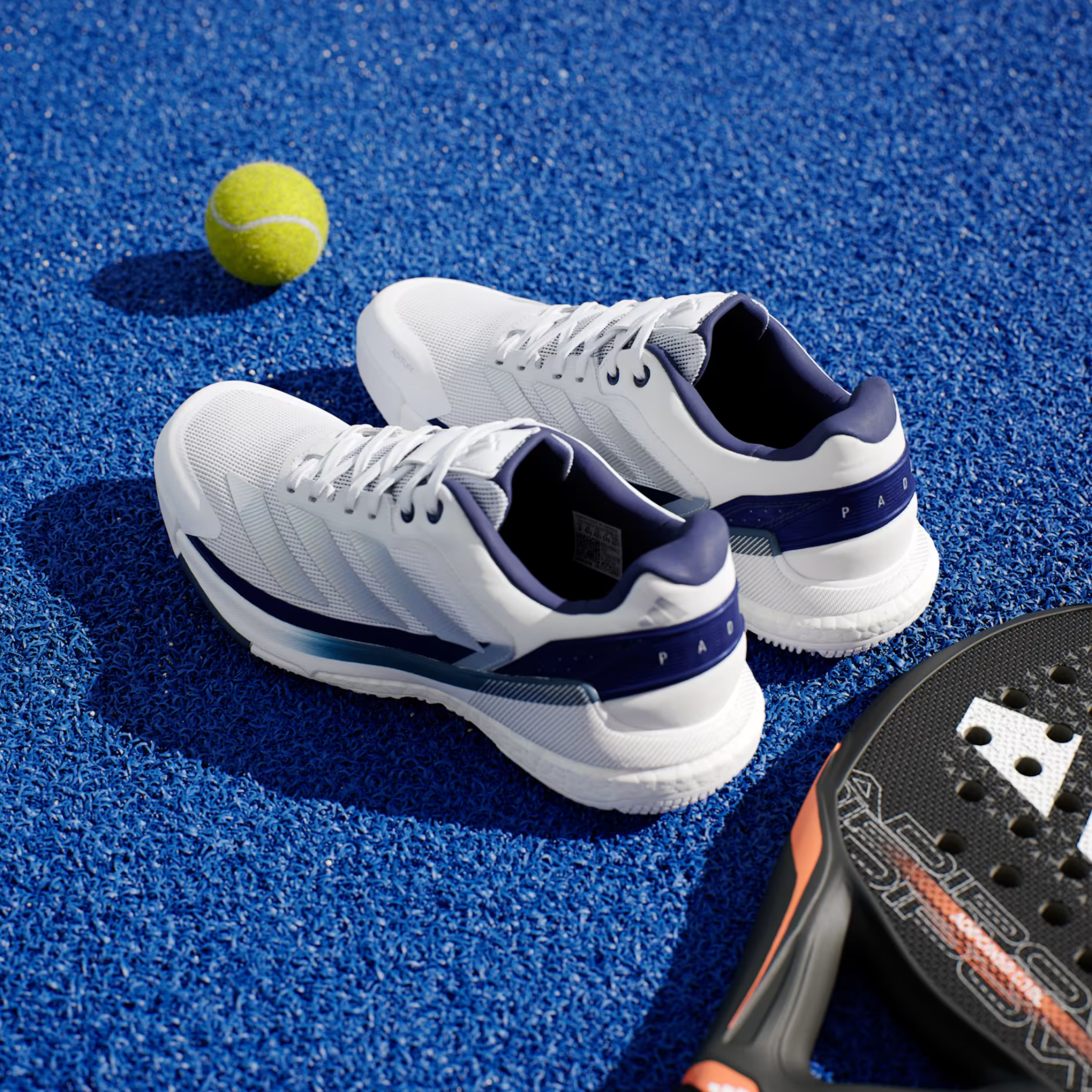 Adidas Crazyquick Boost padel shoes, pair on a blue court with racket and balls